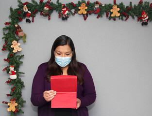 black hair latin woman with protection mask and gift box in christmas decoration, new normal...