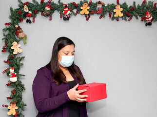 black hair latin woman with protection mask and gift box in christmas decoration, new normal...