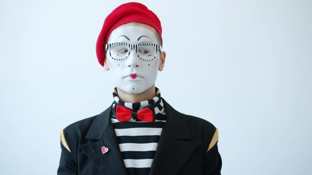 Slow motion of funny mime artist rolling eyes with serious face standing on white background alone wearing funny costume. Facial expressions concept.