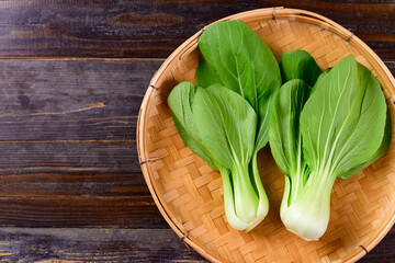Fresh Bok Choy or Pak Choi (Chinese cabbage) in bamboo basket on wooden background, Organic vegetables
