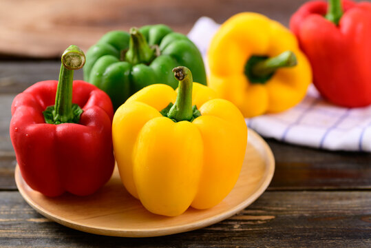 Fresh yellow, red and green bell peppers on wooden background, Organic vegetables
