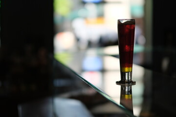close up a glass of cocktail on glass bar counter with colorful bokeh