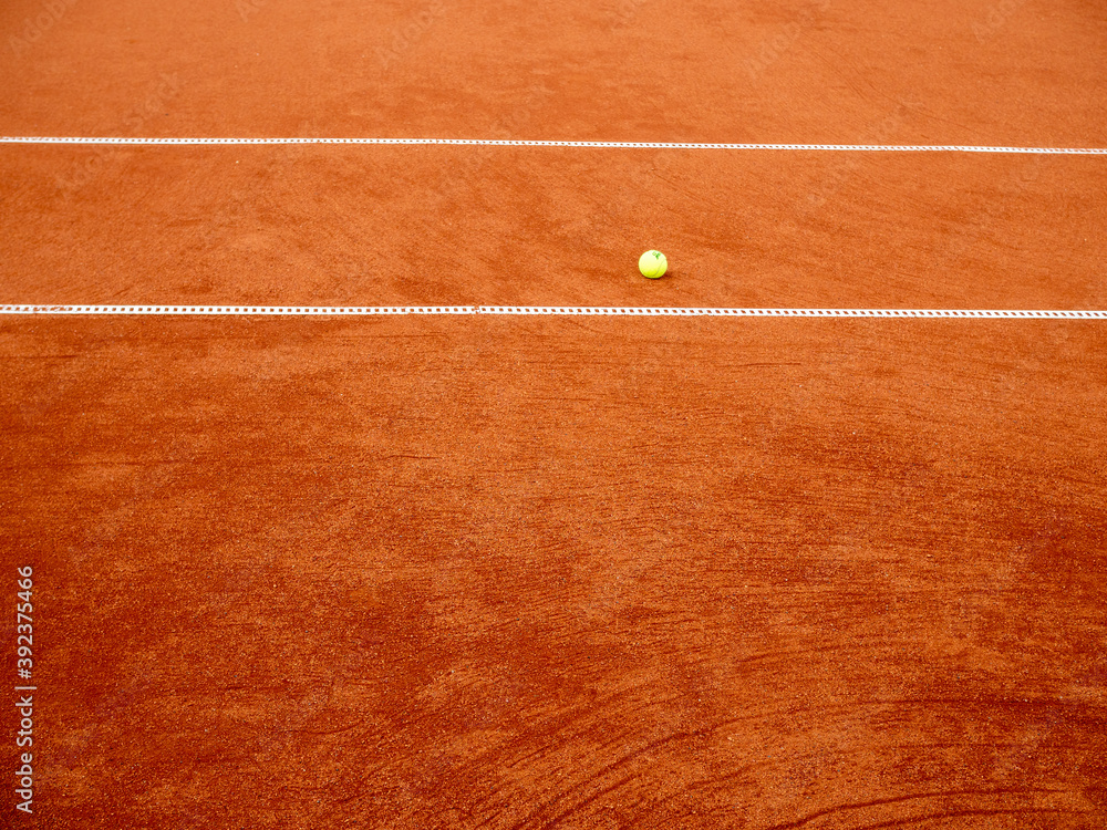 Wall mural Ball for tennis laying on a red tennis clay court