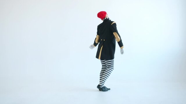 Male mime performer in bright clothing and beret is dancing alone and gesturing looking at camera on white background. Pantomime show and creativity concept.
