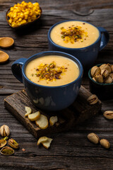 Two bowls of cream of corn soup with pistachios and croutons on top, vertical image, Vegan cuisine. Restaurant menu, dieting, cookbook recipe