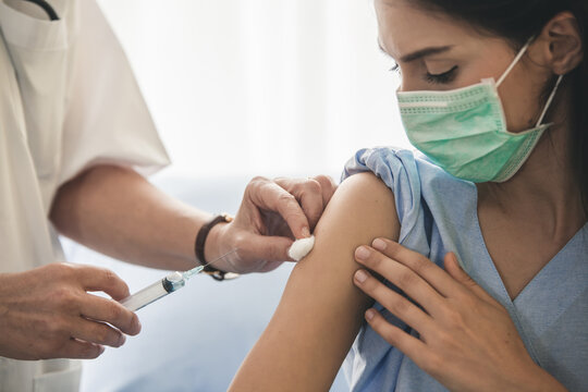 Doctor giving patient vaccine, flu or influenza shot or taking blood test with needle. Nurse with injection or syringe. Cropped image mature doctor in protective gloves making woman an injection