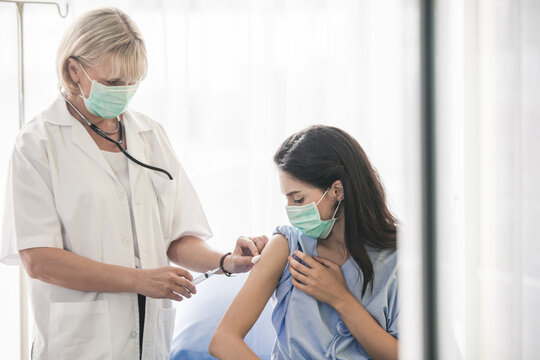 Doctor giving patient vaccine, flu or influenza shot or taking blood test with needle. Nurse with injection or syringe. Cropped image mature doctor in protective gloves making woman an injection
