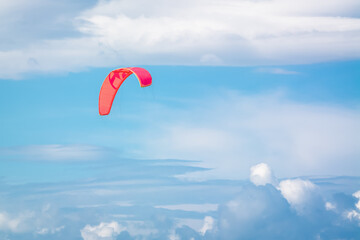 Red parachute with slings in the blue sky with clouds. Parachuting concept.