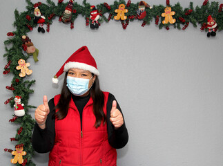 
Latin woman with protection mask, santa claus hat and red vest in Christmas decoration, new normal...