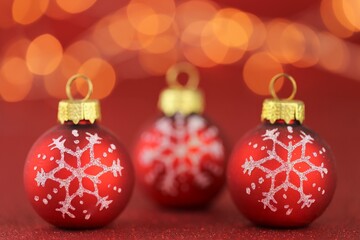 Christmas and New Years festive background.Red balls with a snowflake on a bright red glitter background with bright yellow bokeh. Christmas beautiful festive background. Holidays Beautiful wallpaper.