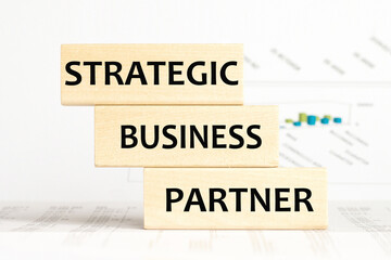 the words STRATEGIC BUSINESS PARTNER are written on a wooden cubes structure. Cube on a bright background. Can be used for business, marketing, financiaL, INSURANCE concept. Selective focus.
