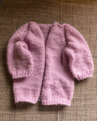 knitted jacket for a girl, pink color, knitting texture, handicraft concept, hand knitting, autumn