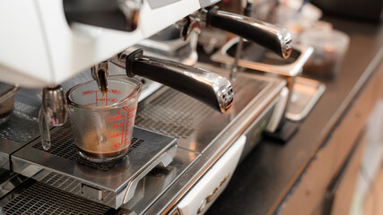 Fototapeta na wymiar black coffee in measuring cup put on coffee maker