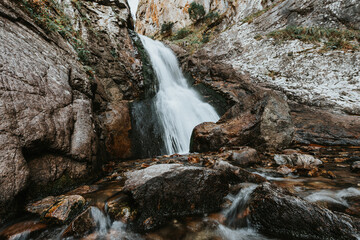 Small waterfall in mountain. Hiking and eco tourism in Caucasus mountain. Travel destinations.