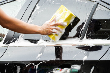 hands hold sponge for washing car.
