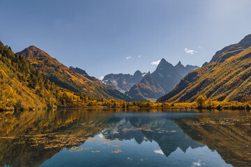 Mountain landscape with lake and blue sky. Reflections on the lake. Autumn in Caucasus mountain.