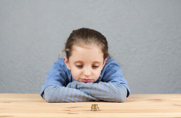 Naklejka premium European girl at the table. Stack of coins. Poverty or small income concept.