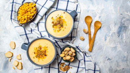 Delicious cream cheese soup with corn, pistachios and croutons on a light background. banner, catering menu recipe. top view