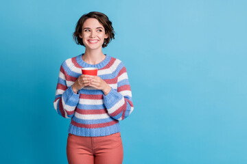 Photo portrait of curious smiling girl keeping red cup of coffee looking at blank space isolated on vibrant blue color background