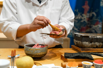 Japanese Sushi Chef making Hand roll temaki sushi of Toro (Fatty tuna). Omakase sushi course.