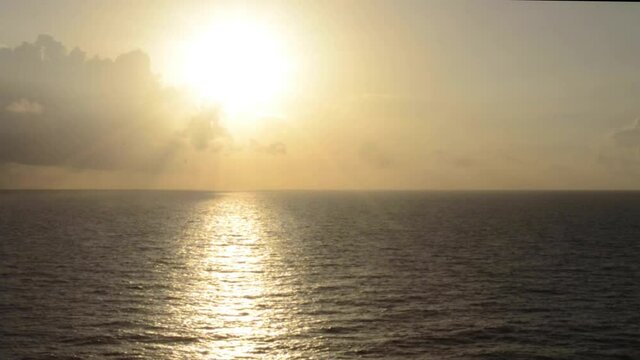 Magnificent display of an evening sun and clouds silver lining the radiating glow that also is reflecting off a vast endless ocean body