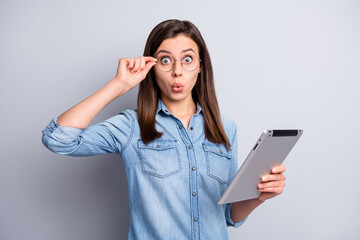 Fototapeta premium Photo of surprised sweet long hairdo girl touch spectacles look tablet wear blue cloth isolated on grey background