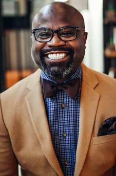 Portrait of confident African American businessman in glasses and tan blazer.