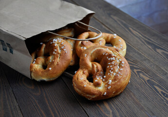 Homemade pretzels in a paper bag on a dark wooden table
