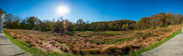 Fototapeta na wymiar A Panoramic Shot of an Open Field With the Sun Behind Trees at Valley Forge With a Wall at the Bottom of the Frame