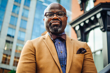 Portrait of confident African American businessman in glasses and tan blazer.