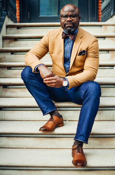 Portrait of confident African American businessman in glasses and tan blazer.