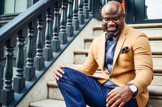 Portrait of confident African American businessman in glasses and tan blazer.