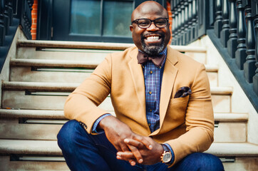 Portrait of confident African American businessman in glasses and tan blazer.