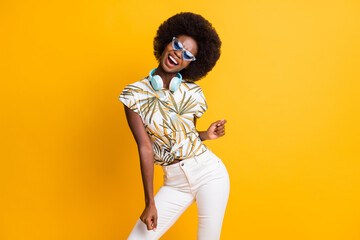 Photo of pretty cute curly hair lady dancing wear headphones spectacles t-shirt trousers isolated over yellow color background