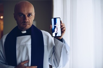 Young priest holding a mobile phone.