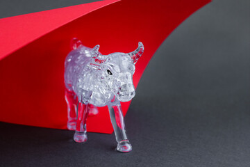 Figurine of a bull from three dimensional puzzles on red and gray background. Symbol of coming New...