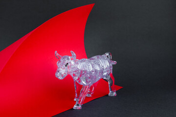 Figurine of a bull from three dimensional puzzles on red and gray background. Symbol of coming New...