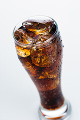 refreshing drink, cold soda with ice cubes in a tall glass on a white background