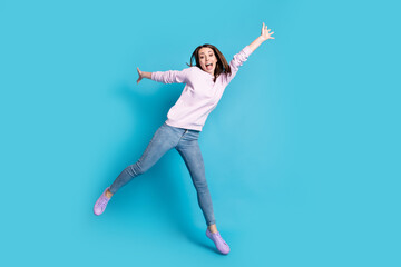 Fototapeta na wymiar Full length photo of excited careless girl jump enjoy crazy funky weekend raise hands wear lilac pullover isolated over blue color background