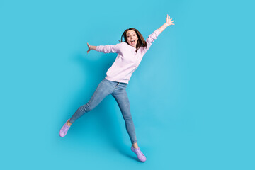 Obraz premium Full length photo of excited careless girl jump enjoy crazy funky weekend raise hands wear lilac pullover isolated over blue color background