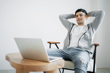 a young stylish designer works at home on a laptop computer, creates architecture and design projects in his comfortable work chair.