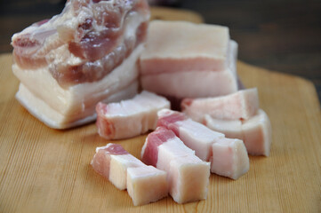 Pieces of fresh pork fat on a wooden board. Close-up