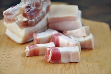 Pieces of fresh pork fat on a wooden board. Close-up