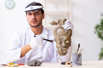 Young male archaeologist studying ancient african stonemask