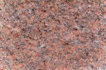 Facing material horizontal background. A red granite slab in close-up can be used as a background. Background of red granite with the texture of the stone.