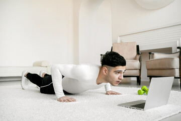 gymnastics fitness cardio workout at home does physical push-up exercises for the body, comfortable sports tight clothing and comfortable white sneakers. athletic man of European appearance.