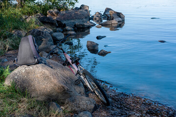 Bicycle and backpack on a rock on the lake shore