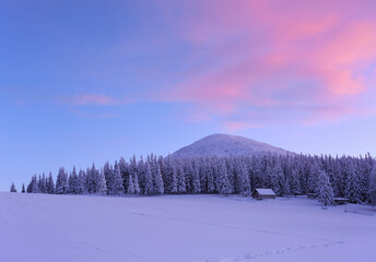 Amazing winter scenery. Old wooden hut on the lawn covered with snow. Fantastic sunrise. Landscape of high mountains and forests. Wallpaper background. Location place Carpathian, Ukraine, Europe.