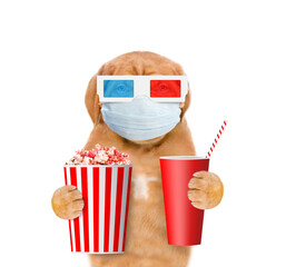 Puppy wearing medical mask holds bucket of popcorn and cola during the coronavirus epidemic....