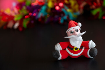 Santa Claus sits on black and beautiful multicolored bokeh background.